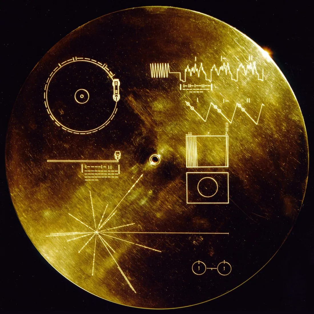 The gold-plated cover of the Voyager Golden Record, engraved with playback instructions, a hydrogen atom diagram, and a pulsar map showing the location of the Sun