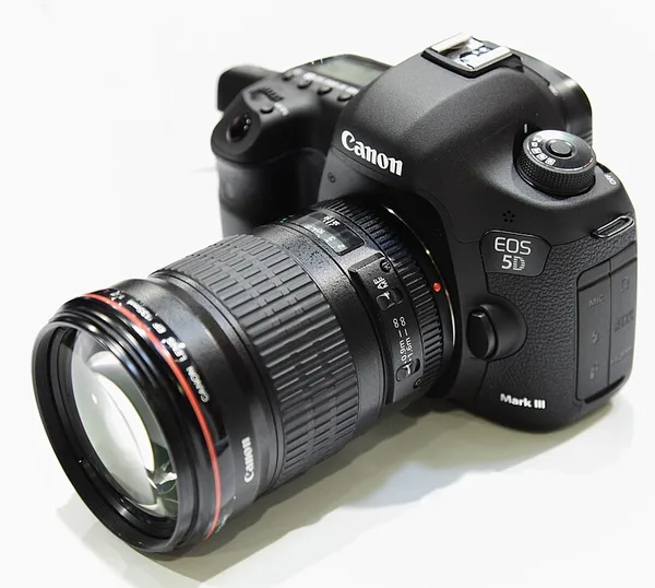 A black Canon EOS 5D Mark III with a large L-series lens, seen from the front at an angle