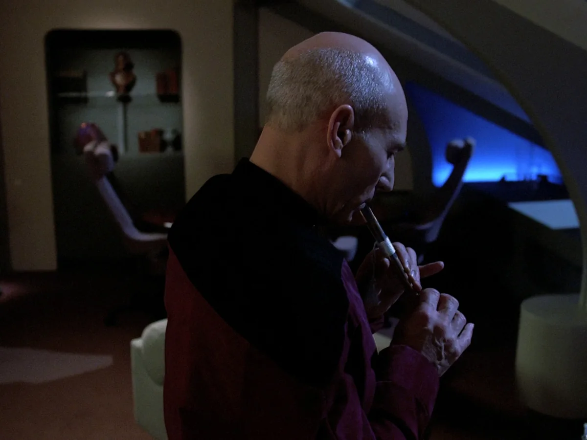Picard alone in his quarters, playing a small flute, lit by blue light from the window