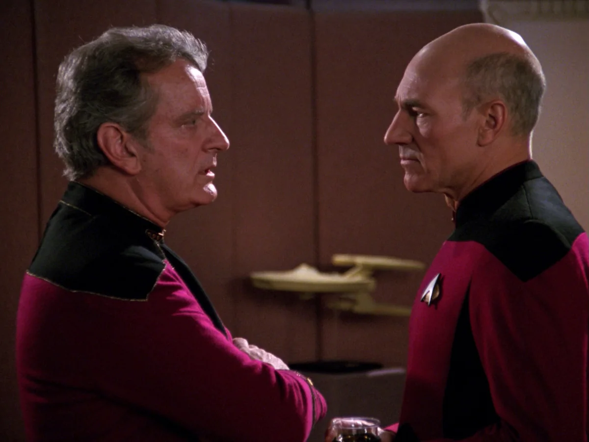 Admiral Haftel and Picard shaking hands in the ready room, a model ship on the shelf behind them