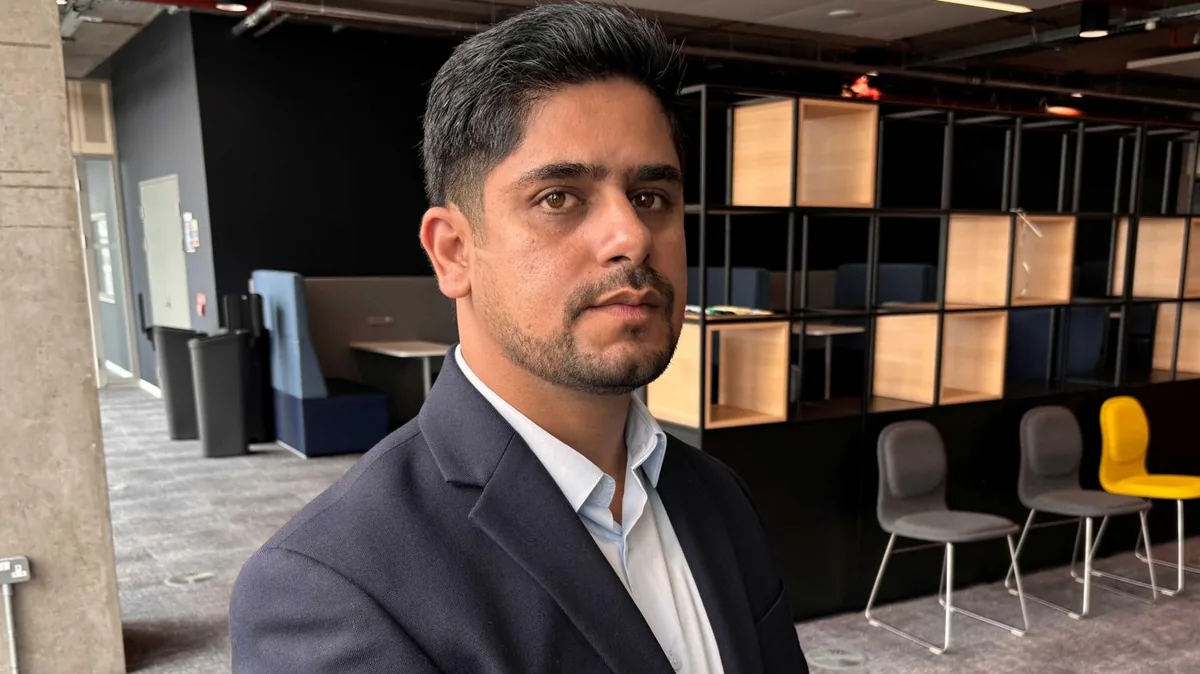 Muhammad Jawad Yaqoob, a man with black hair and stubble in a dark blazer and light blue shirt, photographed in an office, looking at the camera with a neutral expression