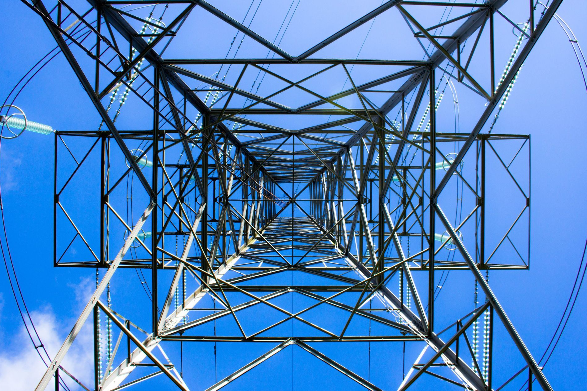 Looking up at an electricity transmission pylon against the sky