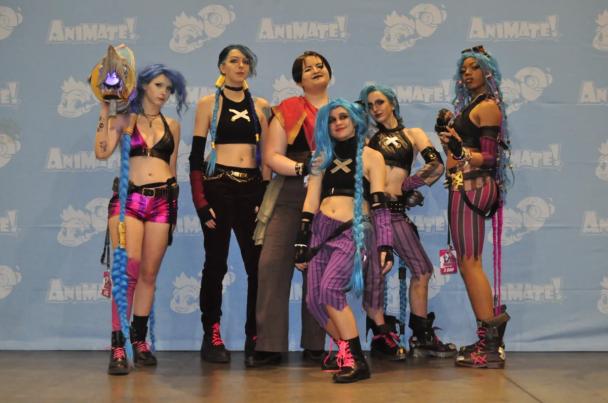 A group of cosplayers dressed as characters from Arcane on a convention stage