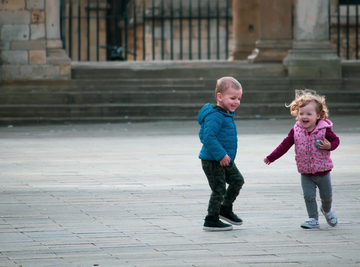 Two children running and laughing in an open square