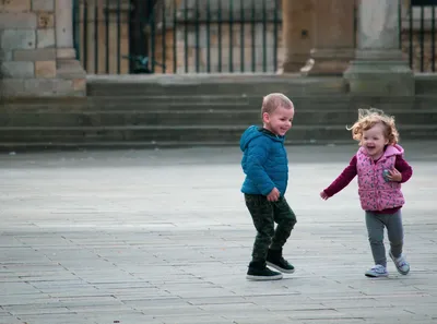 Two children running and laughing in an open square
