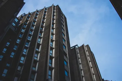 A concrete tower block shot from below against a clear blue sky, rows of windows receding upward