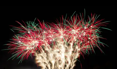 Red, green and gold firework bursts against a black night sky